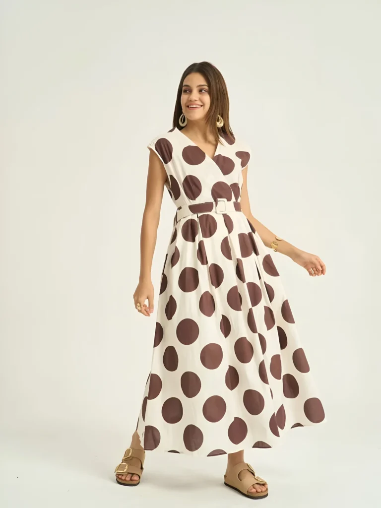Cream polka dot midi dress with the pleated skirt caught in movement